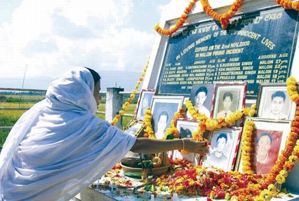 A women offering floral tributes to the victims of the Malom Massacre